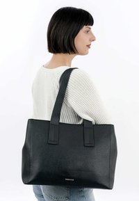 Zwarte leren shopper met een gestructureerde afwerking, twee stevige handvatten, rechthoekige vorm en subtiele logo-detail aan de voorkant.