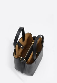 Czarna skórzana torba na ramię z dwoma uchwytami, otwartą górą oraz wewnętrzną przegrodą na zamek błyskawiczny wyłożoną brązowym zamszem.