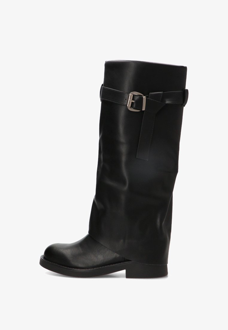 Bota alta de cuero negro con punta redondeada y una correa decorativa con hebilla plateada cerca de la parte superior sobre un fondo blanco.