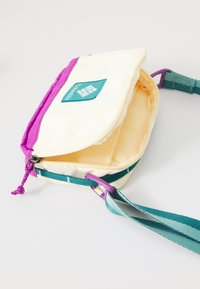 Sac à bandoulière en jaune et violet, fabriqué en tissu résistant. Doté d'une fermeture éclair, d'une sangle réglable turquoise et d'une poche intérieure. Logo Columbia affiché.