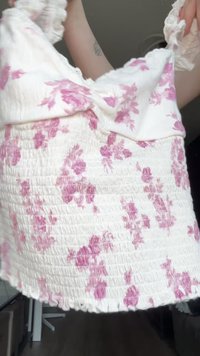 Λευκή floral μπλούζα με  gathered υφή, διακοσμημένη με ροζ λουλούδια και φουσκωτά μανίκια, φτιαγμένη από ελαφρύ ύφασμα.