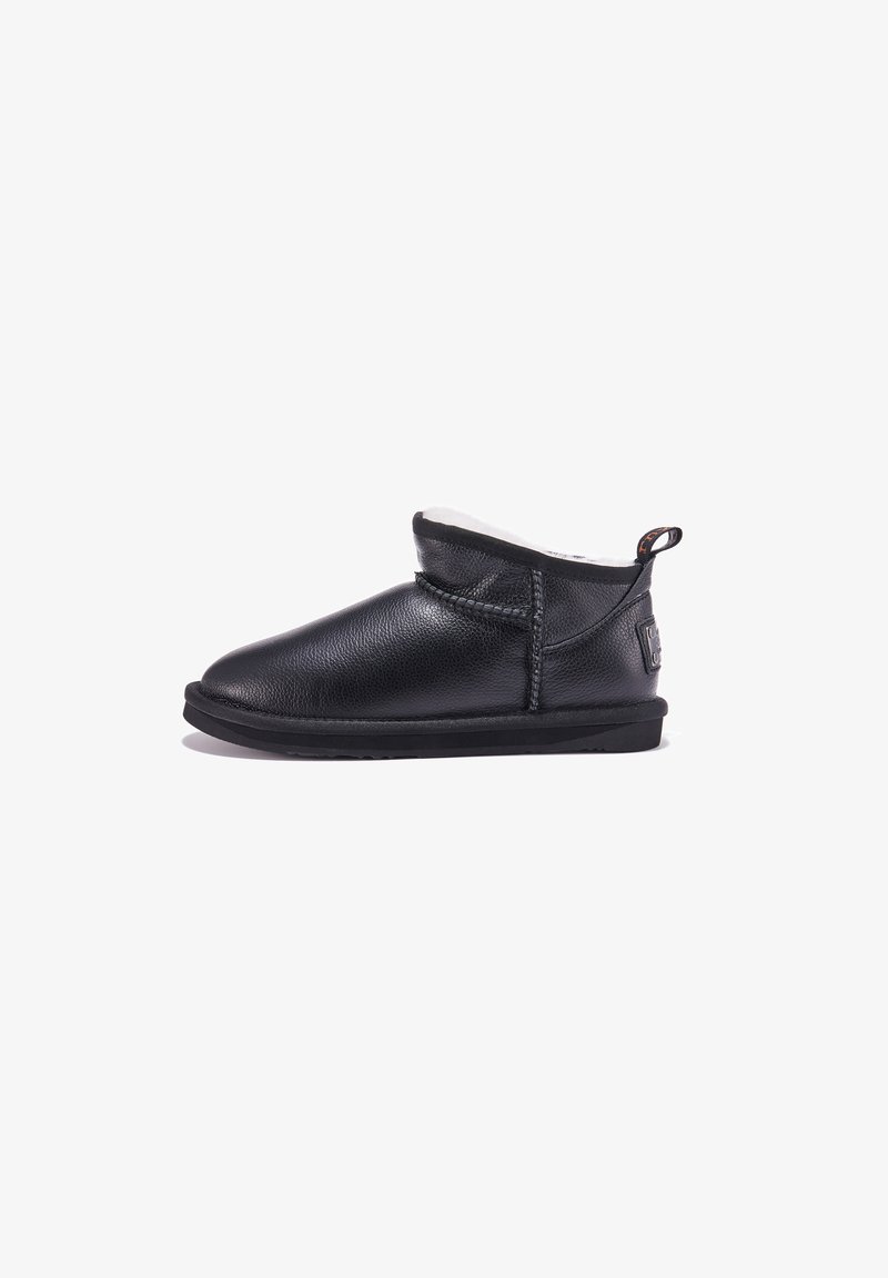 Schwarze Leder-Stiefelette mit weichem weißen Futter, abgerundeter Zehenpartie, niedrigem Profil und einer Schlaufe an der Rückseite. Gummisohle für bessere Bodenhaftung.