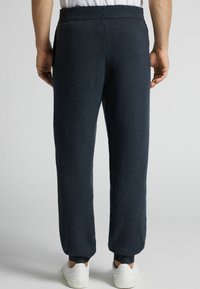 Granatowe dzianinowe spodnie dresowe z elastycznym pasem, zwężanymi nogawkami, ściągaczami u dołu i bocznymi kieszeniami. Miękka tekstura i swobodny fason.