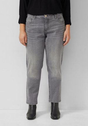 Graue Jeans aus Denim mit relaxtem Schnitt, verblasster Textur, fünf Taschen und Knopfverschluss. Kombiniert mit schwarzen Knöchelstiefeln.