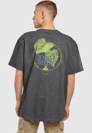 Dark gray oversized t-shirt featuring a green and blue plant graphic on the back, with a circular text design surrounding it.