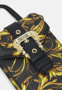 Czarna i żółta torba z wzorem w stylu Versace, wykonana z jeansu, z pozłacaną biżuterią, z misternym zapięciem oraz fakturowaną powierzchnią.