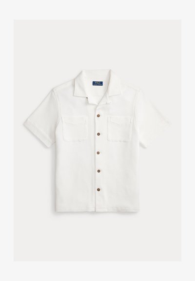 Hvit kortermet skjorte med knapper i strukturert stoff, med to brystlommer og brune knapper foran. Skjorten har krage.