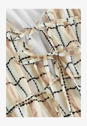 Lehký textilní top s mřížkovým vzorem v béžové, bílé a černé barvě, s pásky na zavazování a jemnou texturou.