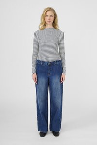 Fekete-fehér csíkos, hosszú ujjú ing, széles lábú kék farmernadrággal párosítva. Simá tapintású, normál derékpánttal és elülső gombos részlettel.