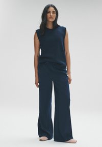Námořnická bezrámovka s kulatým výstřihem v kombinaci s širokými námořnickými kalhotami. Hladká struktura látky, uvolněný střih, jednoduchý design.