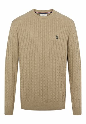 Pull en tricot beige avec un motif en cable, encolure ronde, et des poignets et un ourlet côtelés. Présente un petit logo sombre sur la poitrine.