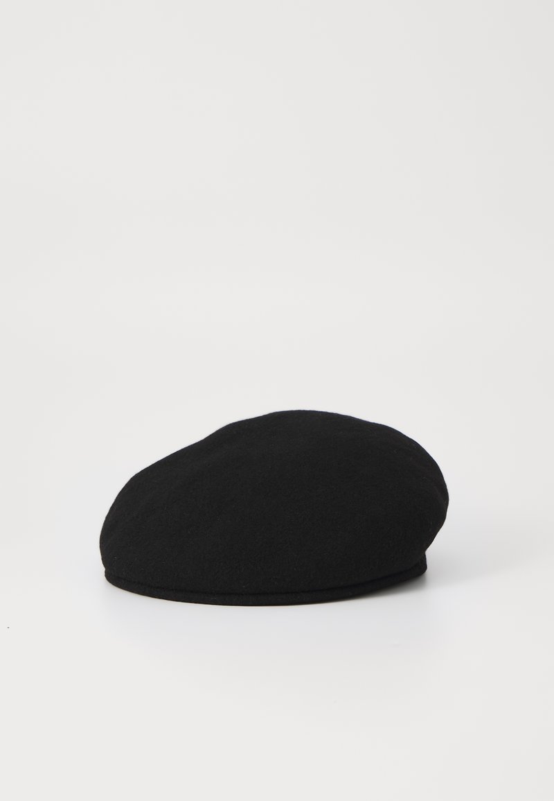 Boina de lana negra con una parte superior redondeada y plana y una textura suave. Presenta un ala delgada a lo largo de la base, presentada sobre un fondo blanco.