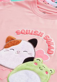 Roza majica z značilno puhasto vezeno zasnovo mačke in medveda, z besedilom "SQUISH SQUAD" v mehurčastih črkah, okrašena s srčki.