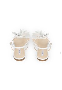 Białe sandały z florystycznym wzorem z przodu, z zapięciem na kostkę i beżową wkładką. Płaska podeszwa z drewnianym akcentem na spodzie.