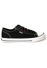 Zapatilla de lona negra con punta y suela de goma blanca, costuras blancas en contraste, cordones negros y acentos en ojal rojos.