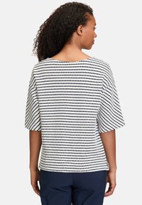 Top a maniche corte di colore bianco con righe orizzontali navy e pois. Vestibilità comoda, scollatura a barca e tessuto testurizzato.