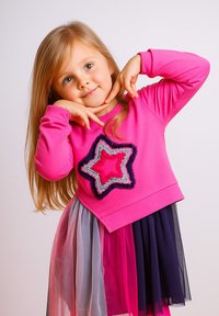 Rosa Langarmshirt mit einem Sternedesign in Rosa und Marineblau, kombiniert mit einem mehrschichtigen Tüllrock in Rosa, Grau und Marineblau.
