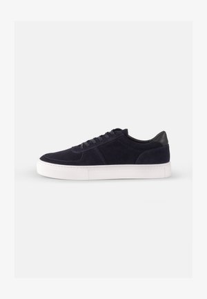 Navy suede sneaker with a white rubber sole, round toe, and classic lace-up design. Features a contrasting black leather heel accent.