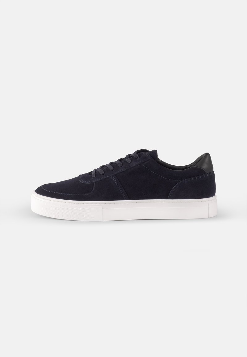 Tengeri suéd sneaker fehér gumitalppal, kerek orral és klasszikus fűzős kialakítással. Kontrasztos fekete bőr sarokdísz jellemzi.