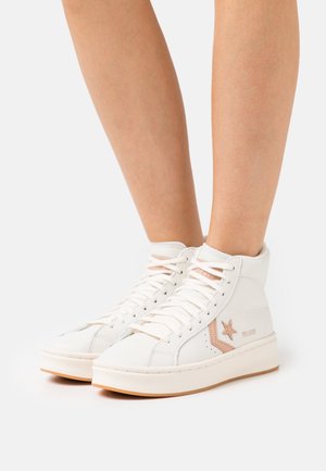 Zapatillas altas blancas de cuero, con un acabado texturizado, detalles en rosa y una suela de goma con un sutil diseño de logo en forma de estrella.