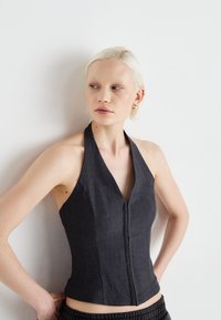 Mørkegrå halterneck-top med V-hals-design, tætsiddende silhuet og synlige sømme. Materialet ser tekstureret ud med en struktureret finish.