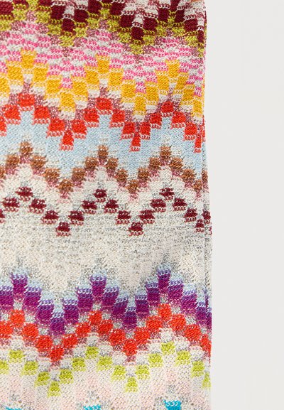 Πολύχρωμο πλεκτό ύφασμα με ζιγκ-ζαγκ μοτίβα σε κόκκινο, κίτρινο, πορτοκαλί, μωβ, μπλε και πράσινο σε ανοιχτό φόντο.