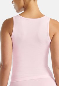 Lichtroze tanktop van zachte stof, met een getailleerd ontwerp, een ronde halslijn en smalle bandjes, die een gladde textuur laat zien.