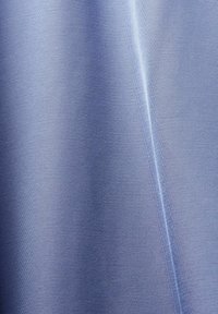 Tissu bleu clair lisse avec une couture diagonale subtile et des ombres douces mettant en valeur sa texture et ses plis.