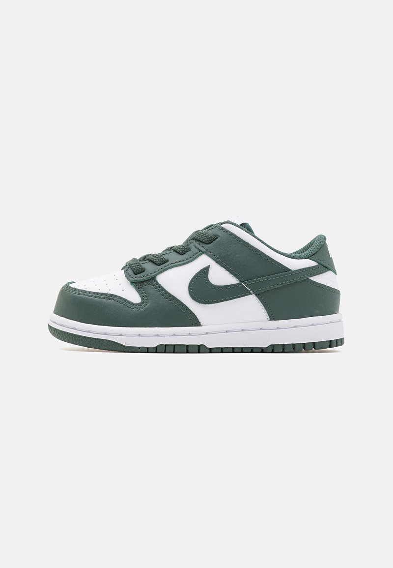 Zapatilla baja en cuero blanco y verde oscuro con el logo de Nike, cordones y suela texturizada sobre un fondo blanco liso.