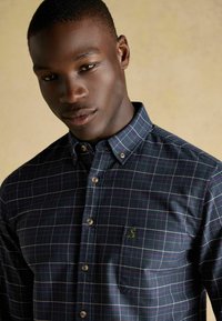 Hemd in Marineblau mit Karomuster in Grün, Pink und Weiß. Mit Brusttasche und kleinem Logo.