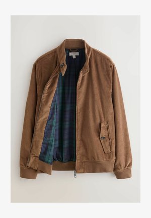 Barna kordbársony dzseki, cipzáras elülső résszel, patent gallérral és oldalsó zsebekkel. Belseje sötétzöld és kék kockás bélésű.