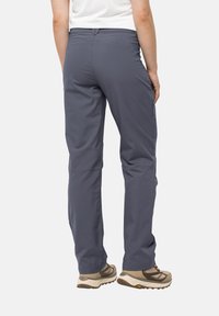 Gray outdoor pants with a straight cut, featuring a zippered pocket on the right hip, paired with light-colored hiking shoes.