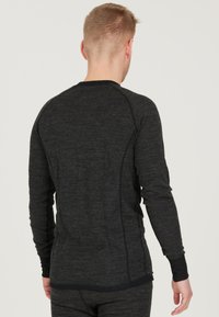 Langærmet thermotop i m�ørkegrå med struktureret stof. Har raglanærmer og sorte manchetter, hvilket fremhæver et tætsiddende design.
