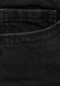 Črn denim material z mehko teksturo, ki vključuje šiv podrobnost na zadnjem žepu in subtilne barvne variacije po materialu.