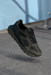 Black athletic shoe with mesh panels, rubber sole, and bold laces. Features textured accents and "REPLAY 1981" branding on the side.