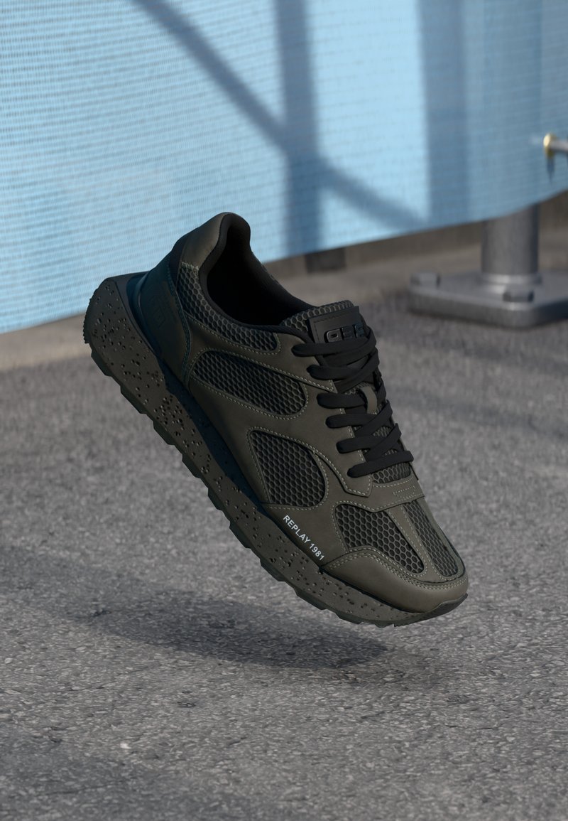 Black athletic shoe with mesh panels, rubber sole, and bold laces. Features textured accents and "REPLAY 1981" branding on the side.