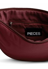 Bustina in tessuto bordeaux con cerniera e una tasca interna con cerniera etichettata con un tag nero che dice "PIECES."