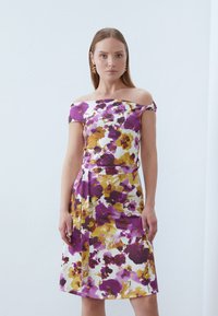 Schulterfreies Blumenkleid mit lila und gelben Aquarellmustern auf weißem Grund, knielang, mit tailliertem Oberteil und ausgestellt Rock.