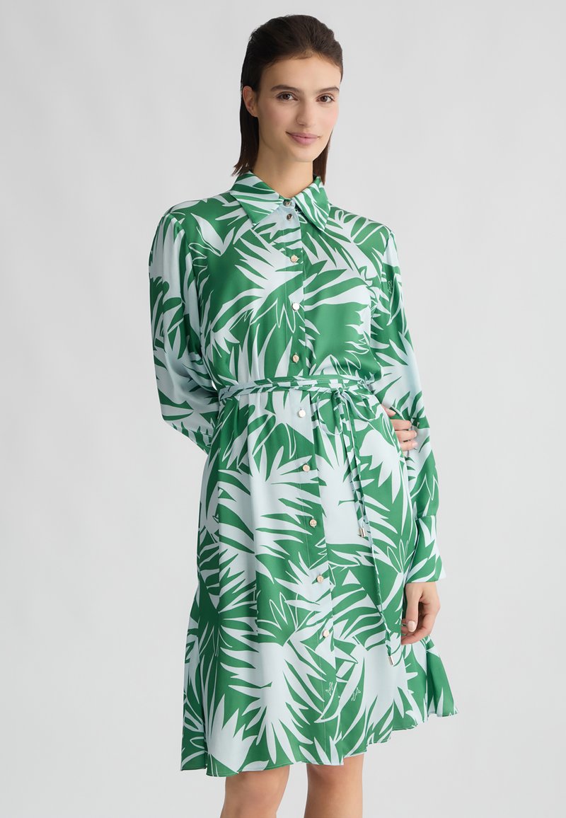Vestito verde e azzurro chiaro con motivo a foglia di palma, maniche lunghe, chiusura a bottoni e una cintura abbinata in vita. Tessuto morbido.