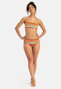 Randig bikini-set i orange, grön och vit. Texturerad tyg med en minimalistisk design. Off-shoulder topp och lågmidjade bottnar.