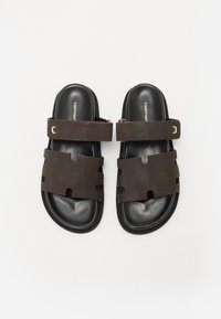 Sandali in pelle marrone con suola in gomma nera, dotati di una larga fascia per le dita e di una fascetta alla caviglia regolabile, accentuati da dettagli in oro.