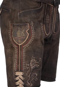 Donkerbruine leren shorts met complexe borduursels, voorzien van een leeuwenembleem, schildenpatch en decoratieve veters aan de voorkant.