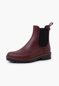 Bottines Chelsea en caoutchouc bordeaux avec des panneaux latéraux élastiques noirs et des semelles texturées. Présente une couture brune contrastante le long du bord de la semelle.