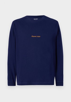 Mörkblå långärmad skjorta med "Originals Studio" broderat i guld på bröstet, presenterad mot en enkel vit bakgrund.