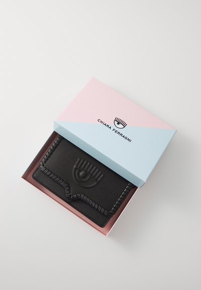 Black leather wallet with embossed eye design, housed in a pastel pink and blue box with "Chiara Ferragni" logo.