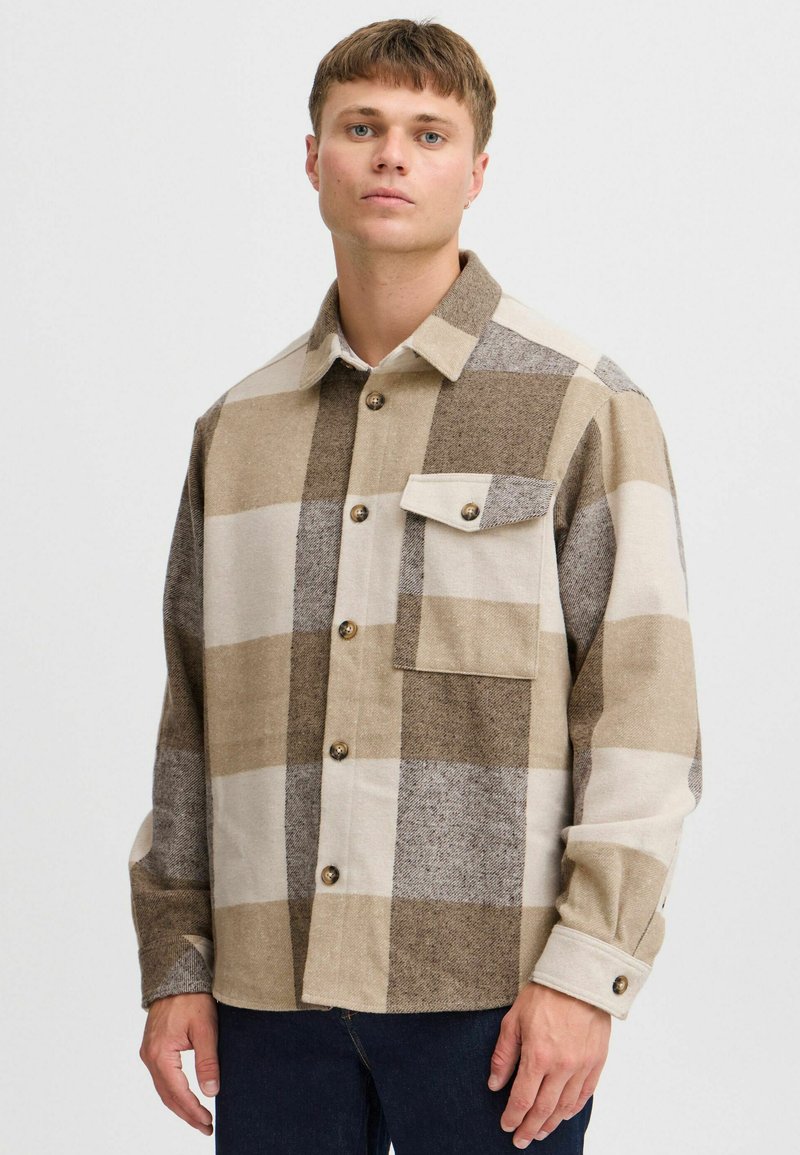 Camicia di flanella a quadri in tonalità beige e marrone, con taschino anteriore, chiusura con bottoni e colletto. Tessuto morbido con una vestibilità rilassata.