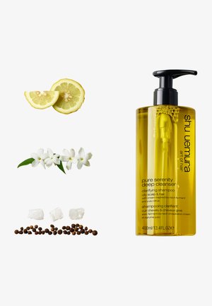 Klärendes Shampoo in einer transparenten gelben Flasche mit schwarzem Pumpkopf, verziert mit Zitronenscheiben, weißen Blumen und salzkristallähnlichen Kristallen.