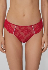 Red lace panties with floral pattern, sheer fabric, and contrasting side accents featuring small rhinestones for decorative detail.