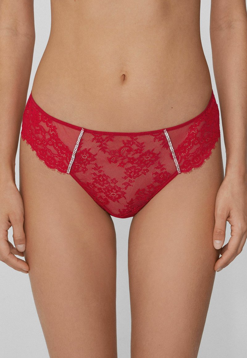 Red lace panties with floral pattern, sheer fabric, and contrasting side accents featuring small rhinestones for decorative detail.