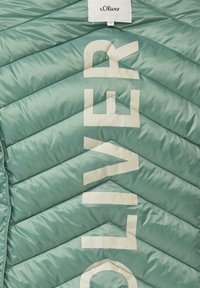 Lekka, turkusowa kurtka puchowa ze wzorem w jodełkę; posiada wyraźne białe logo na przodzie oraz tkowaną metkę przy karku.